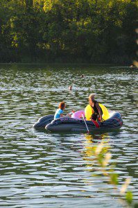 2 Kinder fahren Schlauchboot auf dem Badesee in Pfuhl